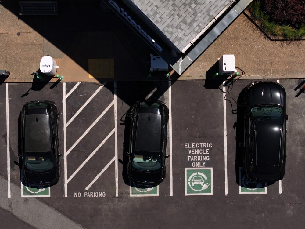 In an aerial view, electric cars sit parked at a charging station in Corte Madera, Calif., on May 15. Federal tax credits that have encouraged the purchase of electric vehicles could be phased out, depending on what happens with negotiations over the Republican tax and spending package currently before the Senate.