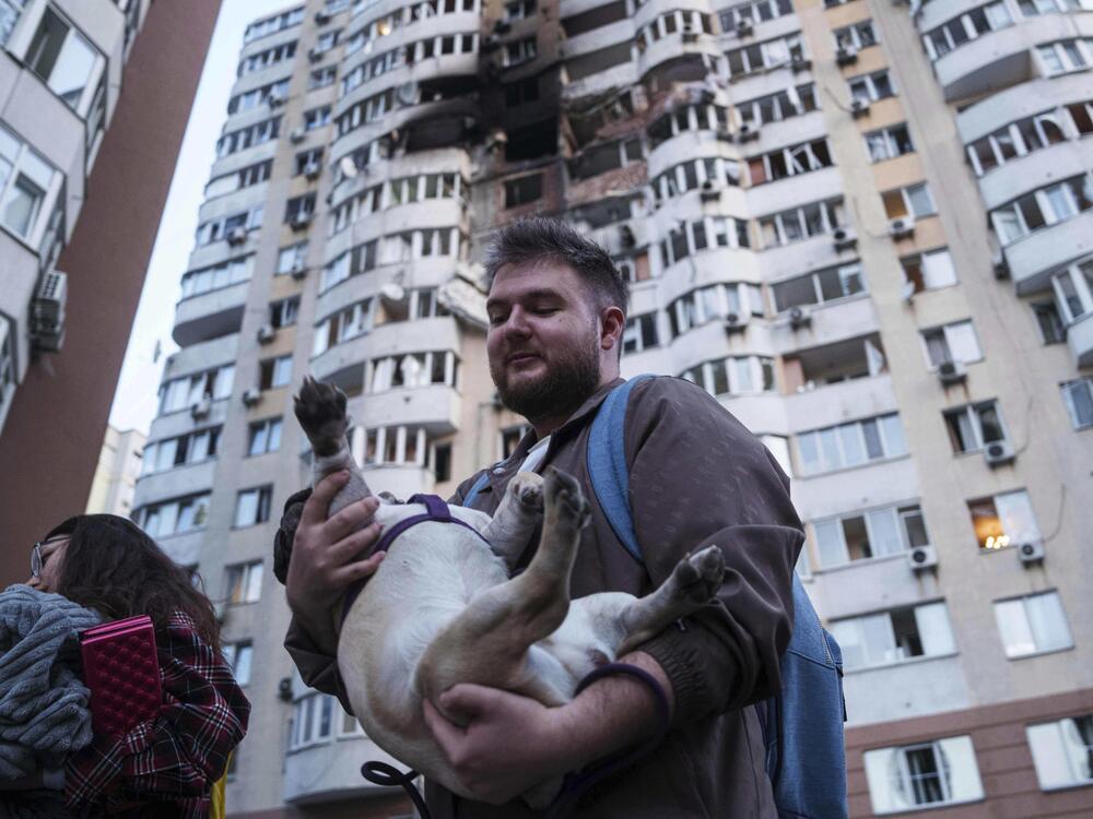 A man carries his dog in front of a residential multi-story building damaged after a Russian drone strike on Kyiv, Ukraine on Friday.
