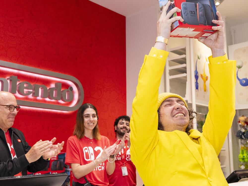 Nintendo of America President Doug Bowser sells a Nintendo Switch 2 system to a Christopher Evangelista, a fan who says he camped out for two months outside Nintendo New York to be first in line for the console.