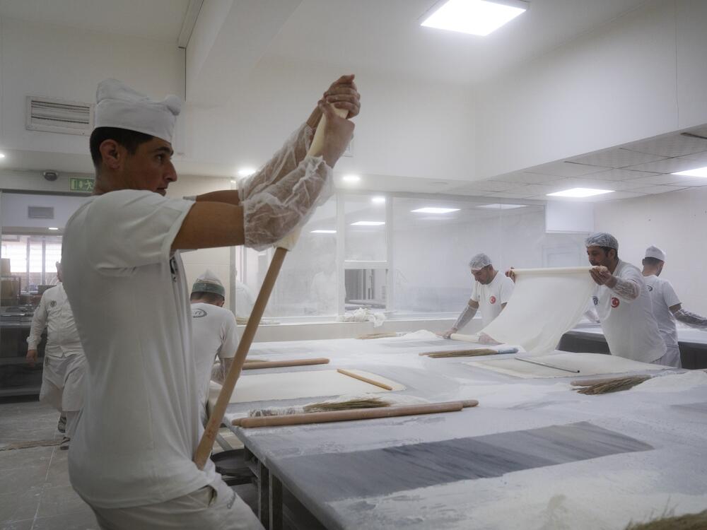 Bakers roll and stretch dough into paper-thin sheets for baklava at the factory of Celebiogullari.