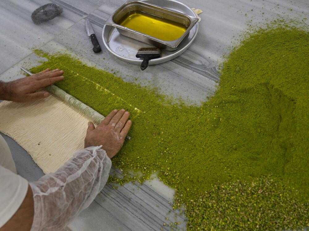 A baker rolls chopped pistachios into baklava dough at the Celebiogullari factory.