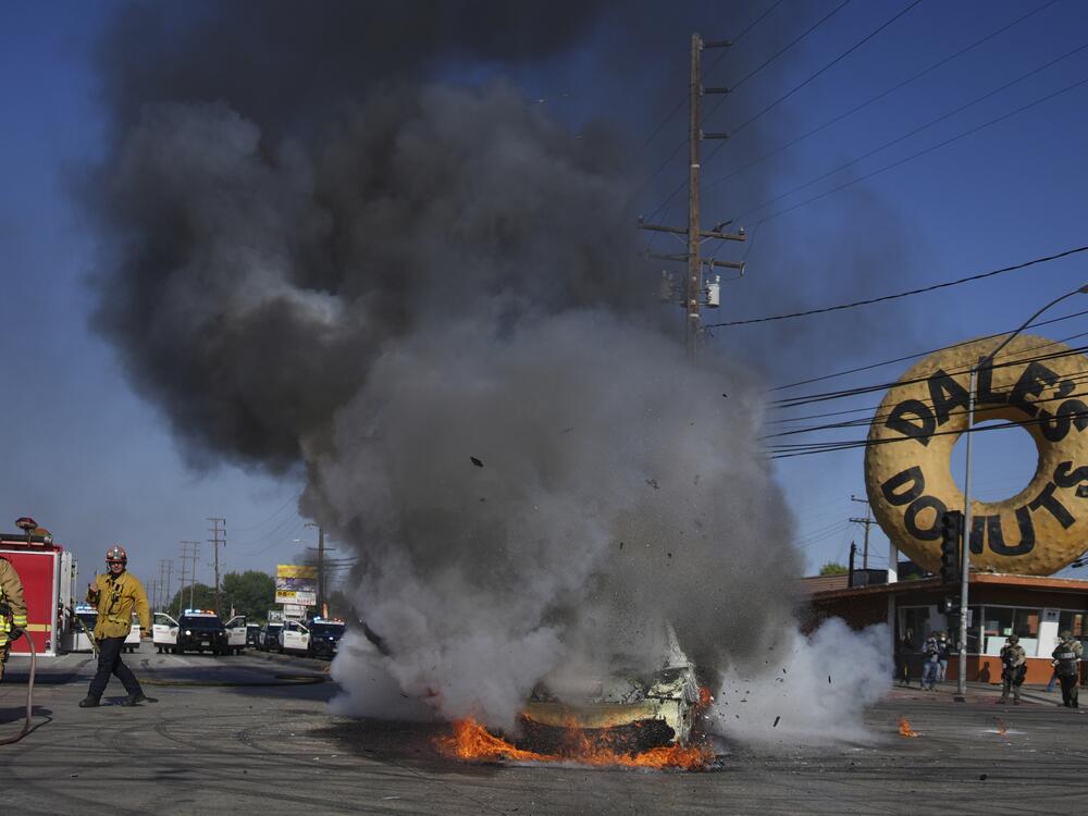 Firefighters respond to a car burning during a protest in Compton, Calif., Saturday, June 7, after federal immigration authorities conducted operations.