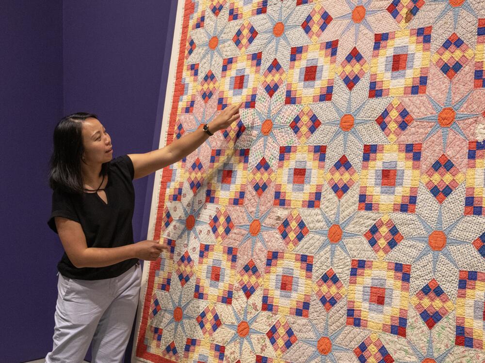 BAMPFA Associate Curator and Academic Liaison Elaine Yau points out details in one of the quilts on display: Rebecca Smith and Bettie Chaffold, <em>Untitled (Shadow Star)</em>;<strong> </strong>Bequest of the Eli Leon Living Trust, BAMPFA‬.