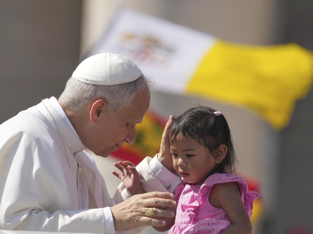 Pope Leo XIV caresses a little girl as he arrives to celebrate a Mass for the Jubilee of New Religious Associations on Pentecost Day in St. Peter's Square at the Vatican, Sunday, June 8, 2025.