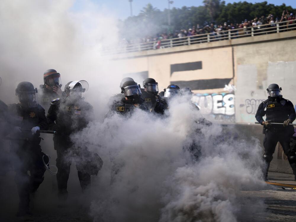 Police are seen through smoke on the 101 Freeway near the Metropolitan Detention Center of downtown Los Angeles.