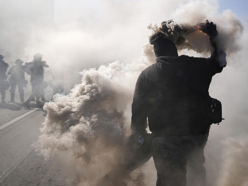 A protester throws a smoke canister on the 101 Freeway nears the metropolitan detention center of downtown Los Angeles.