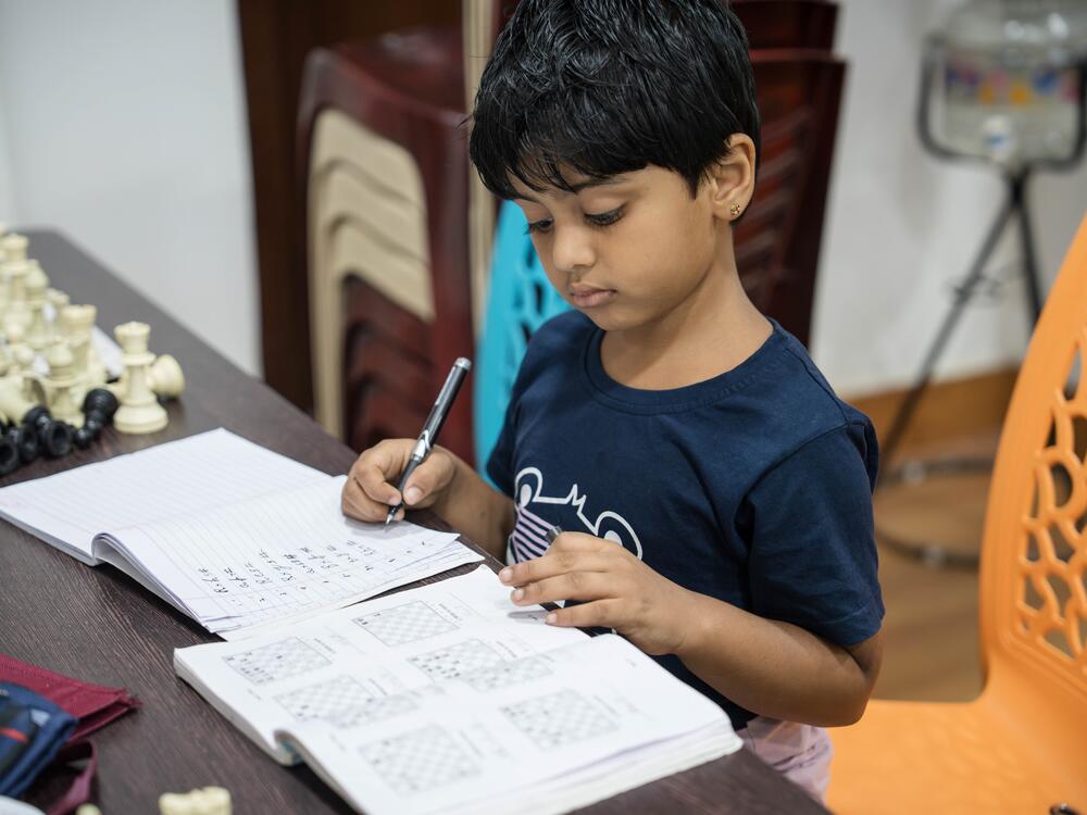 Six-year-old Sriharika, a beginner, studies chess theory while other students play matches following their classes at the Madras school of chess in Chennai