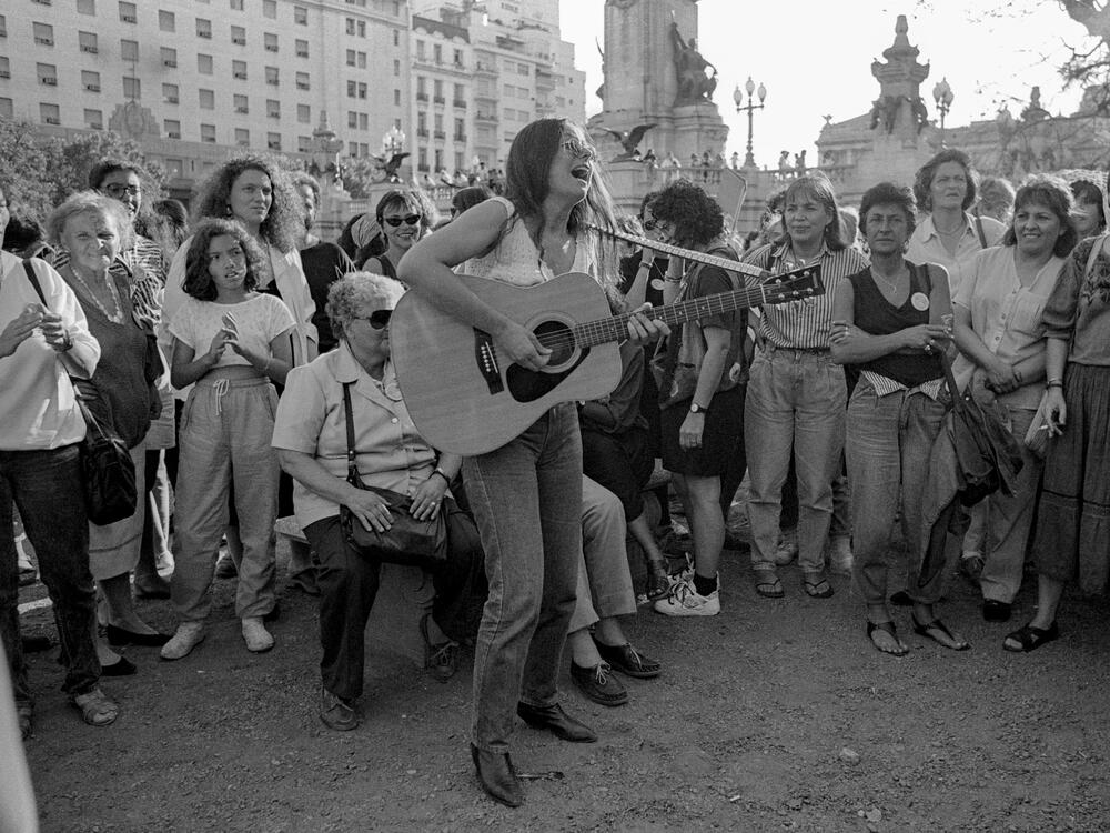 A woman plays an acoustic guitar for participants in the closing march of the 5th <em>Encuentro Feminista Latinoamericano y del Caribe</em> (Feminist Meeting of Latin America and the Caribbean) in San Bernardo, Argentina, on Nov. 24, 1990.