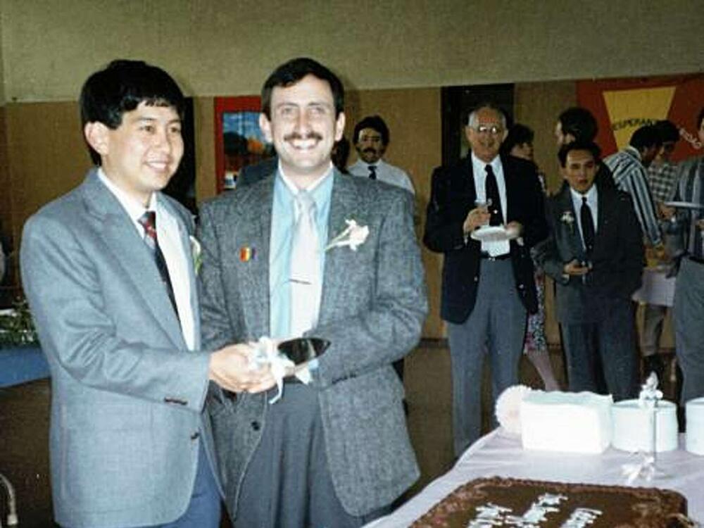 Craig Wiesner and his husband, Derrick Kikuchi, on their wedding day, April 8, 1990, at First Presbyterian Church Palo Alto's Fellowship Hall. The couple is preparing to cut the first slice of cake after the ceremony.