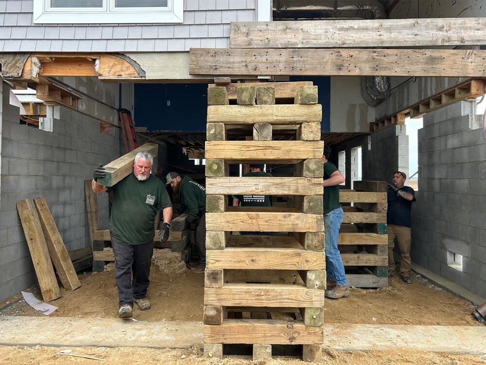 Crew members from Frank Myroncuk & Son, Inc. House Movers take down pilings after lifting a home in Stafford Township. Experts say the cost of raising homes can put it out of reach for some families and communities. New Jersey used federal recovery funds after Hurricane Sandy to help pay for home elevations, but the money was slow to reach some households.