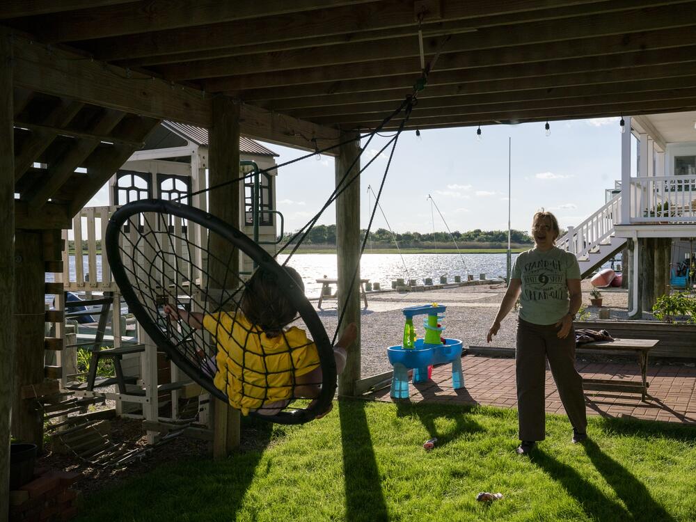 Devecka-Rinear pushes her daughter on a swing underneath the now-elevated home where she visited her grandmother while growing up. She doesn't want to leave the small island where she lives. 