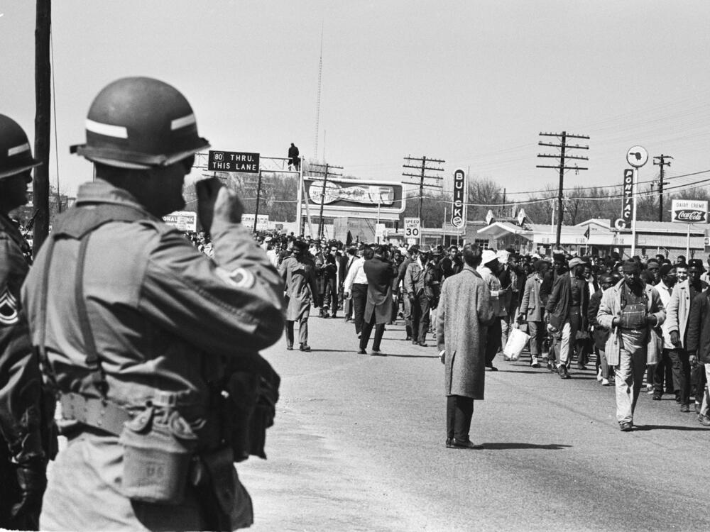 Soldiers watch civil rights protesters walking during the third Selma March in Alabama, on March 25, 1965. President Lyndon Johnson federalized the Alabama National Guard to prevent violence against the marchers.