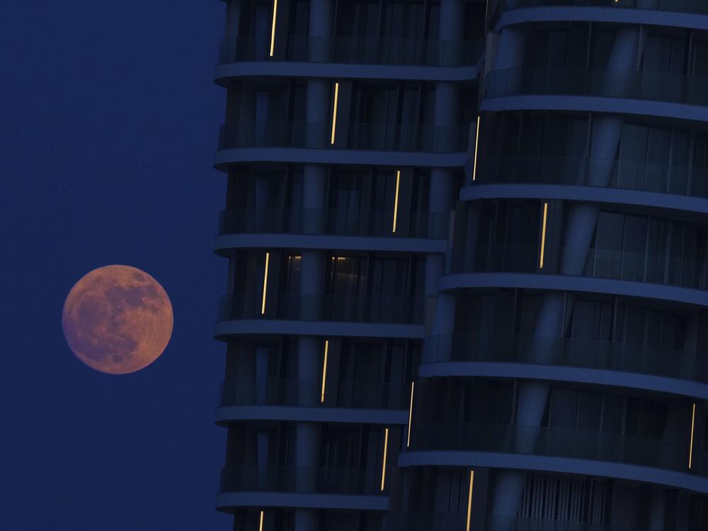The strawberry moon rises behind a tower at a marina in the southeast resort town of Ayia Napa in the eastern Mediterranean island of Cyprus.