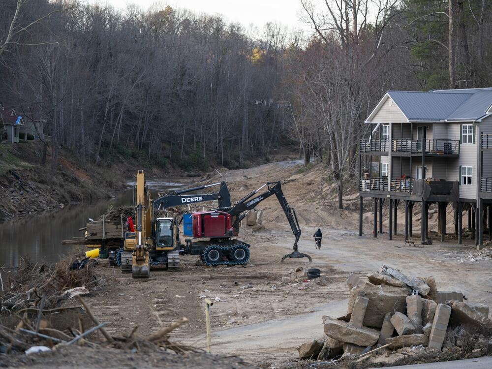Construction vehicles are parked next to a storm-damaged apartment complex where two people died in a landscape scarred by Hurricane Helene near Swannanoa, N.C., on March 24.