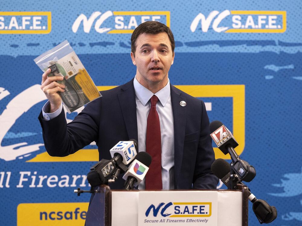 N.C. Attorney General Jeff Jackson holds a gun lock at an event about safe storage of firearms. North Carolina is among 30 states with the most permissive gun laws, according to a new study.