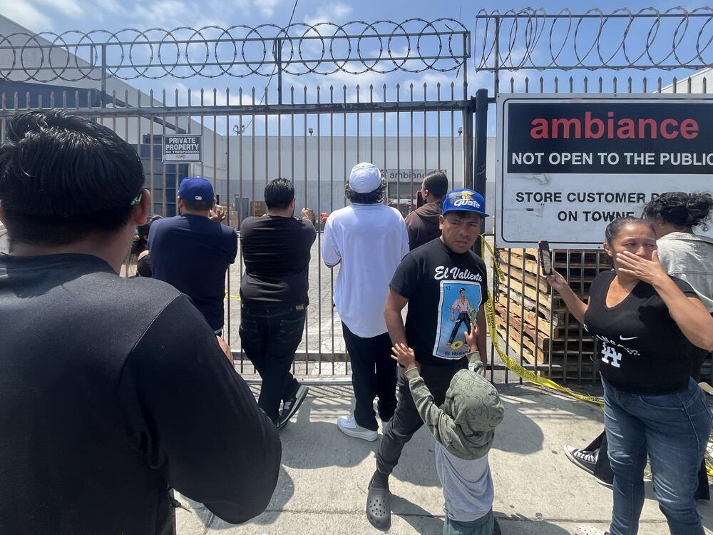 People gather in front of Ambiance Apparel after several employees were taken into custody by federal agents in the Fashion District in downtown Los Angeles on Friday.