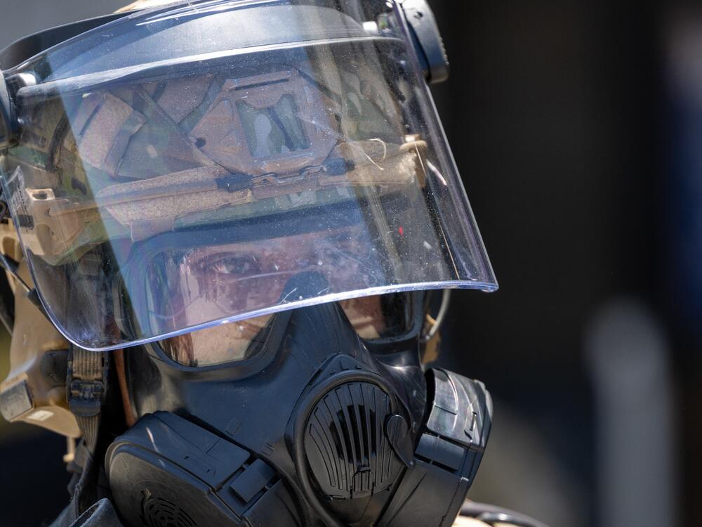 A National Guard officer wearing a helmet with visor and a gas mask stands guard at the Metropolitan Detention Center during an anti-ICE protest in downtown Los Angeles on Sunday.