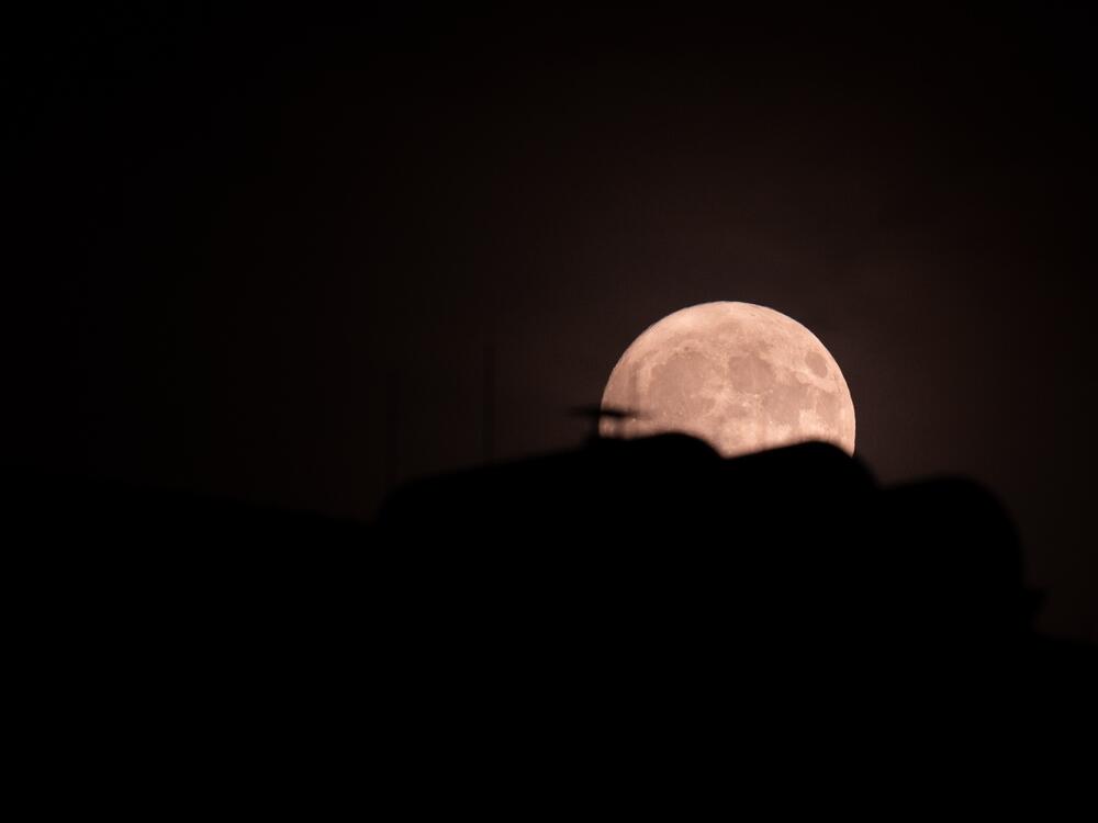 The moon can be seen behind the roof of a house on the night of June 10-11. It's a rare celestial phenomenon known as the strawberry moon. The full moon is then unusually low in the sky - as low as it was 18 years ago.