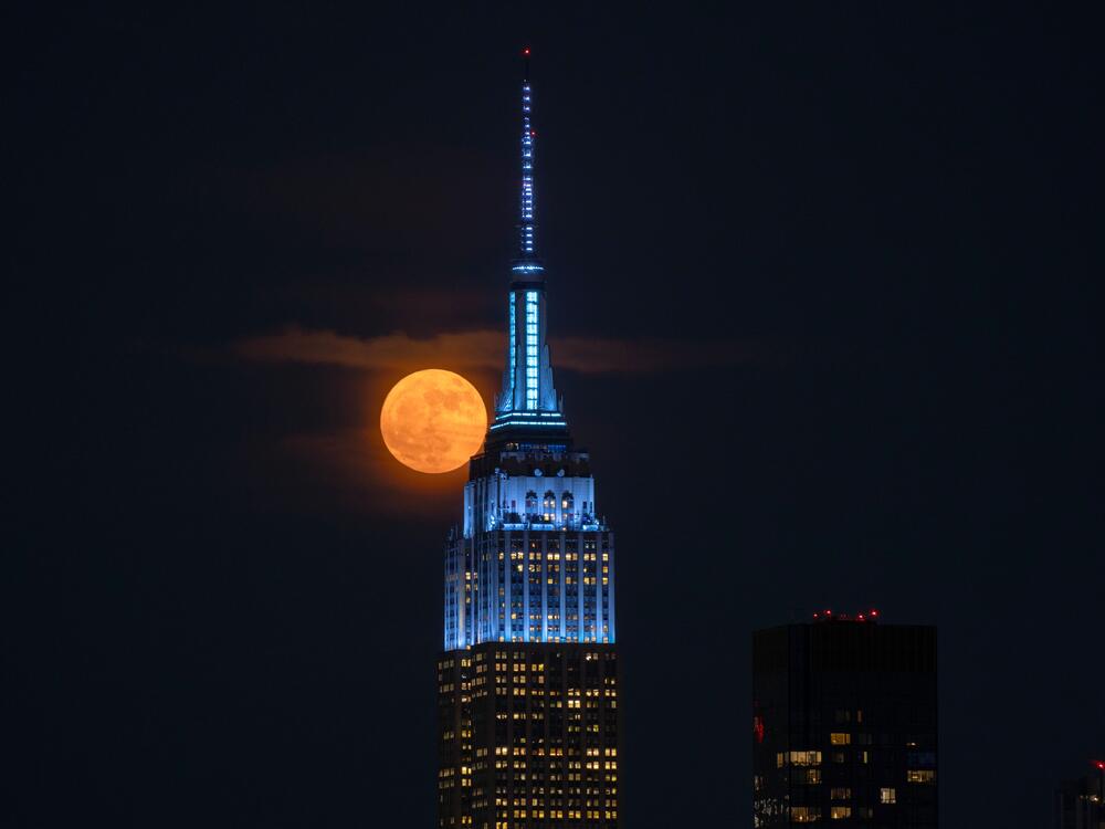 The full Strawberry Moon rises behind the Empire State Building in New York City, as seen from Weehawken, New Jersey.
