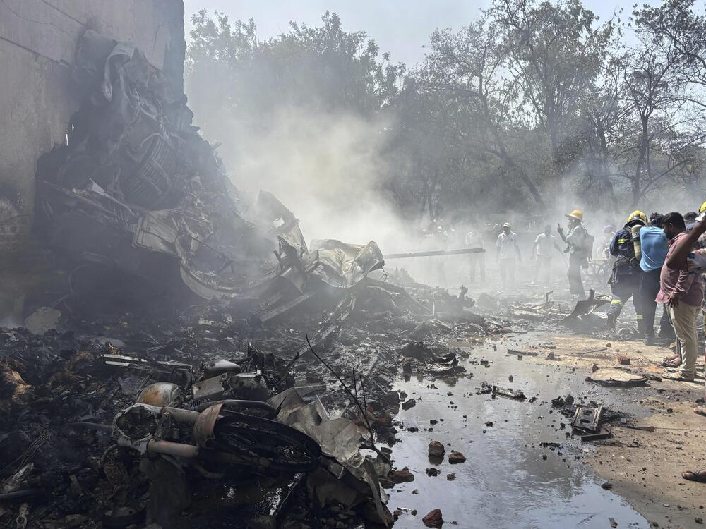 People stand around debris at the site of an airplane that crashed in India's northwestern city of Ahmedabad in Gujarat state on Thursday.