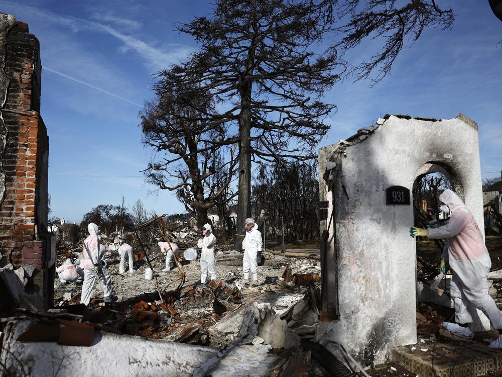 Volunteers help a homeowner search for personal items in the remains of a home that burned in the Palisades Fire in January 2025 in Pacific Palisades, California.