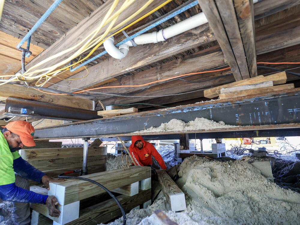 Workers with JAS Builders and Payne Construction Services raise a home with jacks and framing material in May in Treasure Island, Florida. The companies are experiencing a surge in demand as homeowners hire them to elevate their homes in response to increasingly severe hurricanes, storm surges and flooding caused by heavy rainfall.