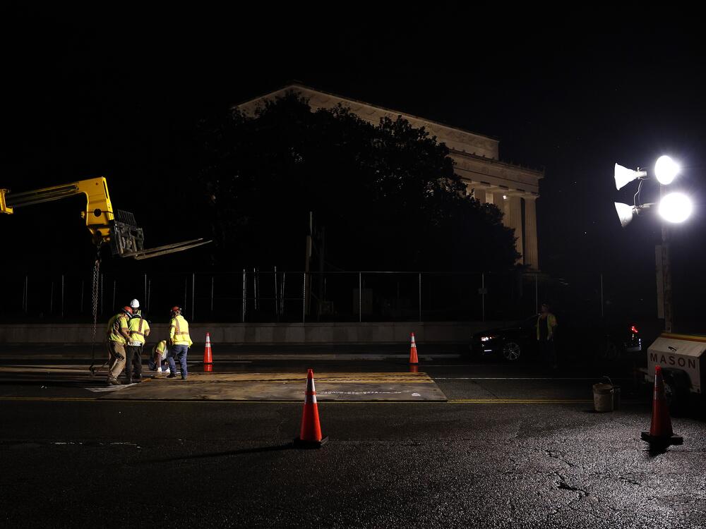 Crews install metal plates to help protect the street from tank damage for the upcoming military parade on June 10 in Washington, D.C.
