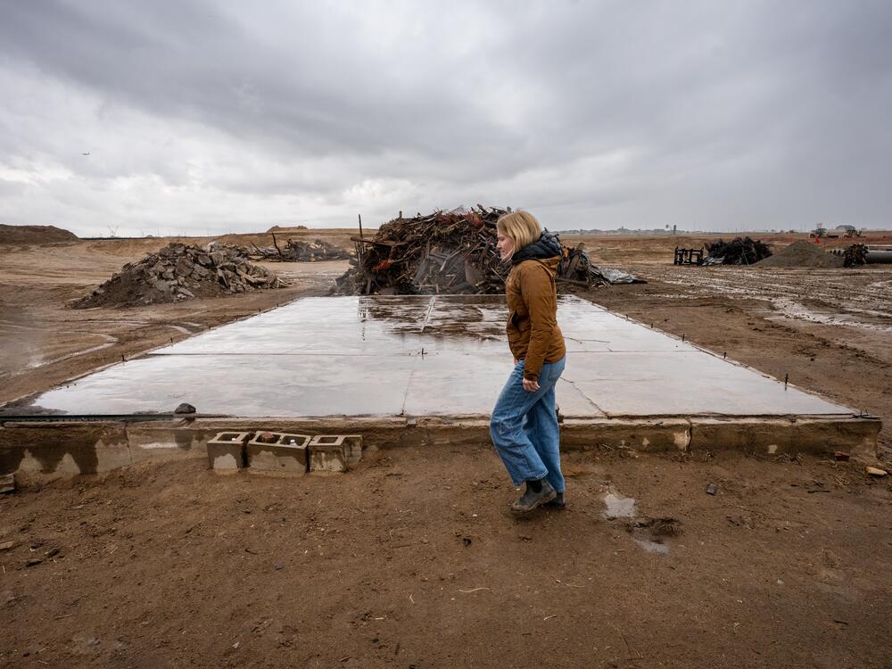 Perks Deconstruction co-owner Anna Perks walks past the remaining slab of an old farmhouse at a project in Aurora.