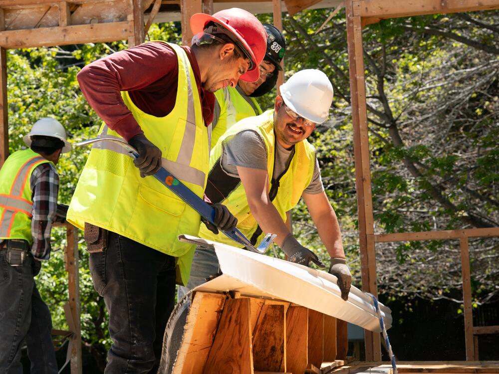 At a project site in Boulder, a Perks Deconstruction crew pulls a metal gutter from a piece of roofing taken off a house.