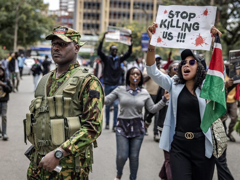 A protester holds a banner and shouts at a Kenyan police officer during a demonstration over the death of Kenyan blogger Albert Ojwang, who died in police custody. June 12 2025