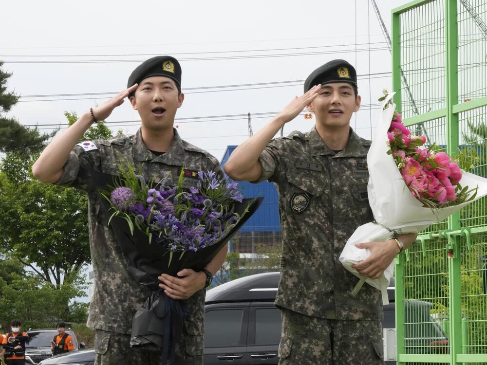 K-pop band BTS members RM, left, and V salute after being discharged from a mandatory military service in Chuncheon, South Korea, on Tuesday.