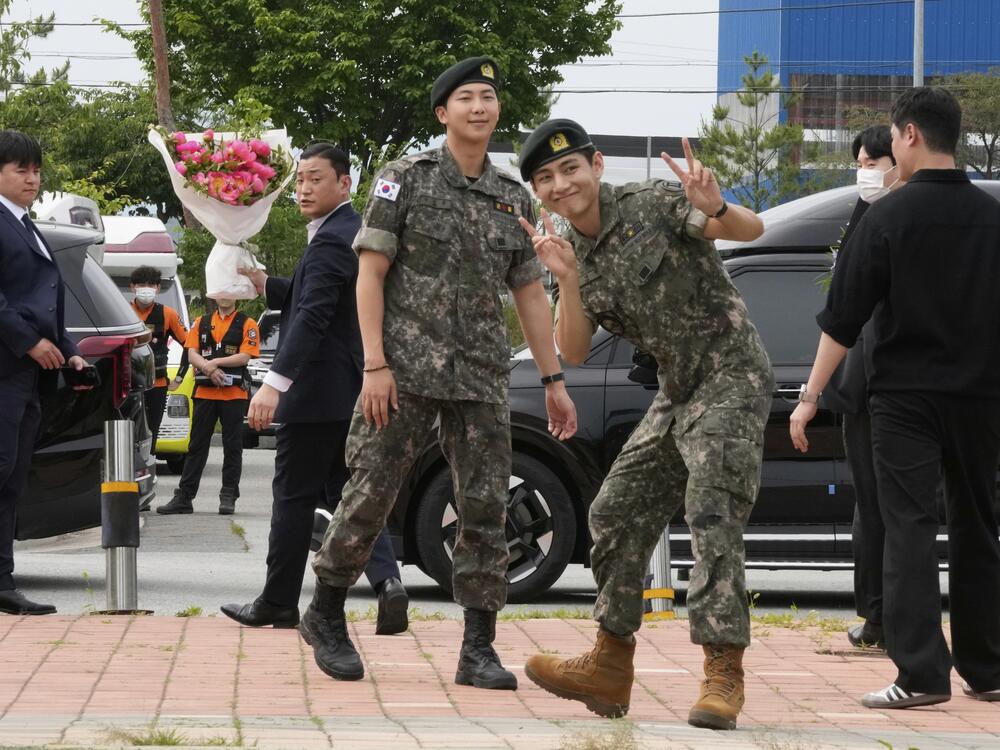 K-pop band BTS members RM, center left, and V, center right, react after being discharged from a mandatory military service in Chuncheon, South Korea on Tuesday.