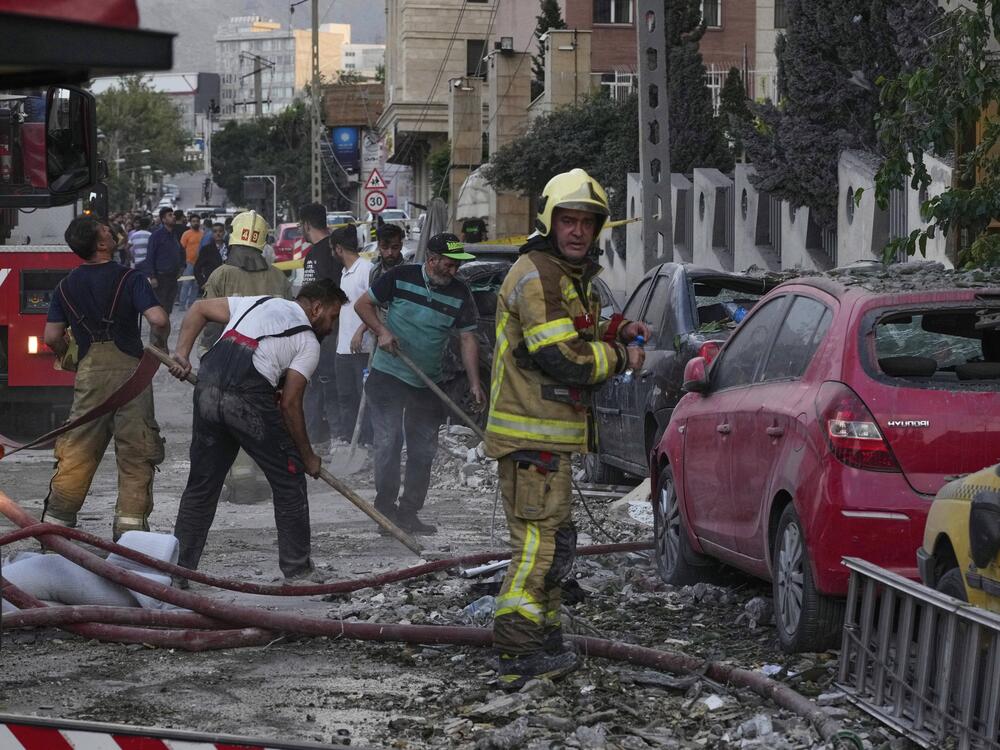 Firefighters and people clean up the scene of an explosion at a residence compound after Israeli attacks in Tehran on Friday.