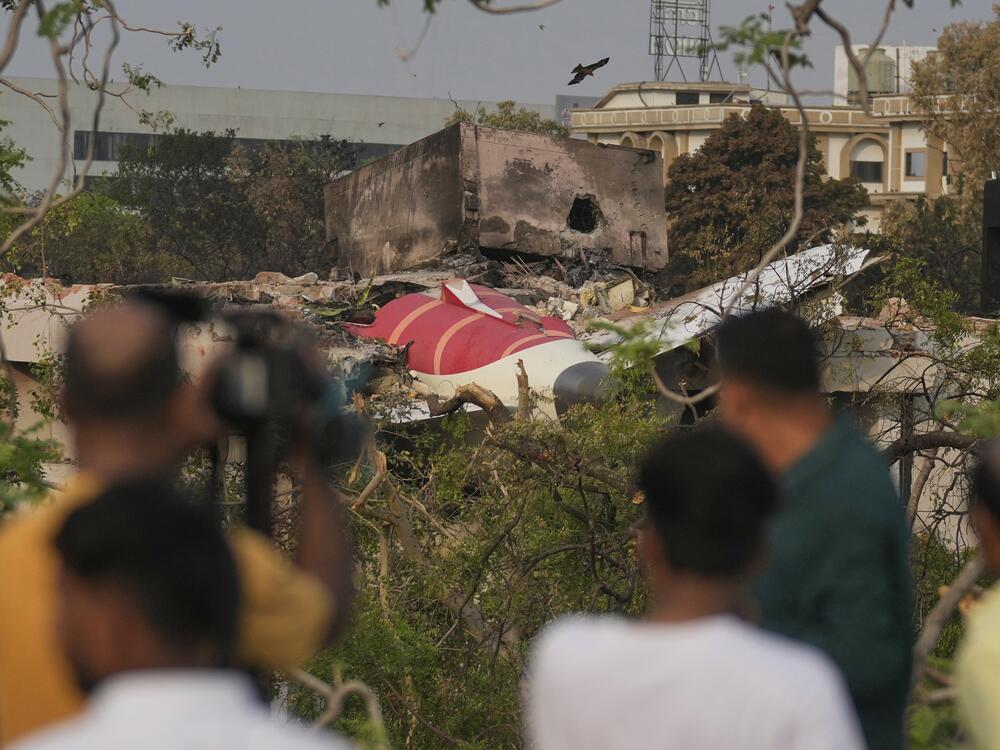 Onlookers watch wreckage from Thursday's Air India plane crash lying atop a building in Ahmedabad, India, on Saturday.