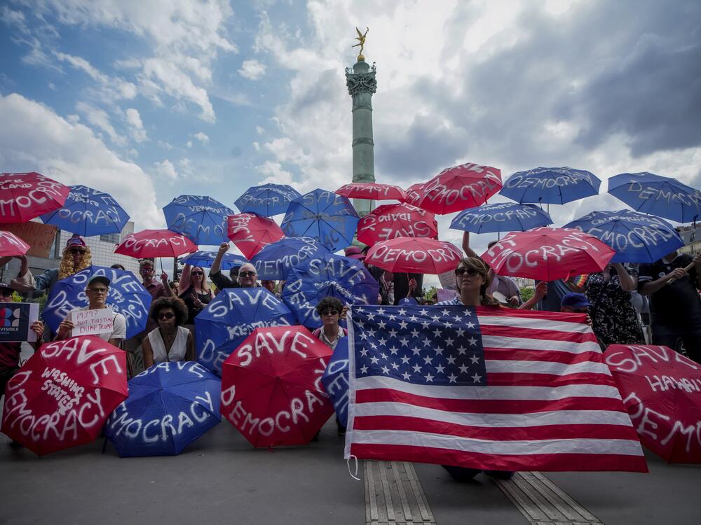 Paris, France: People holding umbrellas reading save democracy take part in the No Kings protest.