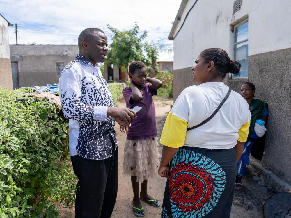 Pastor Billy speaks with Salome Mwale, a neighbor who also helps care for Diana (center).