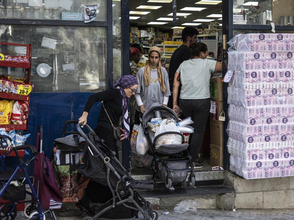 A woman pushes a stroller full with goods as people stock up with supplies, at a shop in Jerusalem, on June 13, 2025.