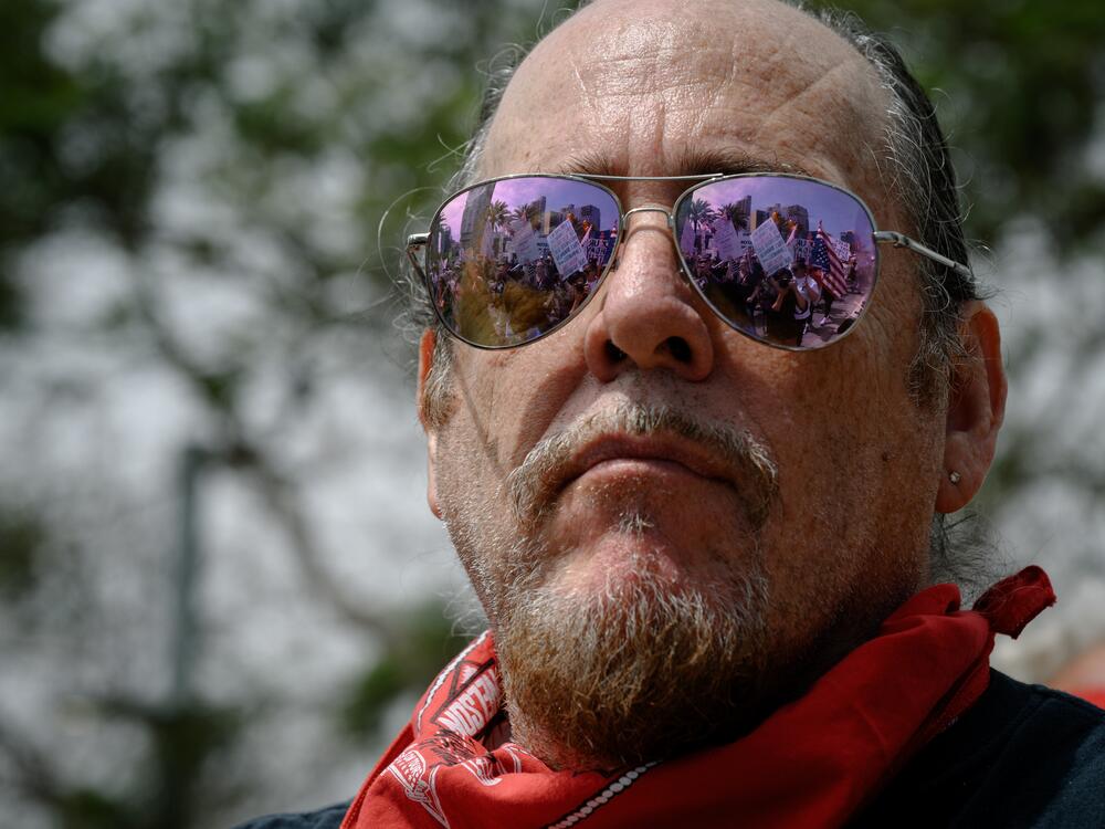 San Diego: A musician watches as thousands of protestors, reflected in their sunglasses, march through downtown.