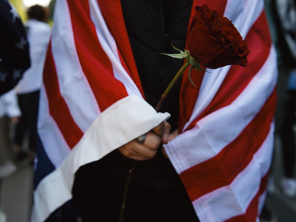 Seattle: Imelda, a demonstrator, holds a red rose while draped in an American flag while protesting.