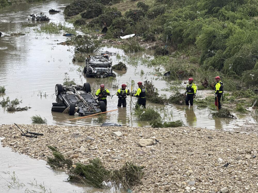 Authorities respond after vehicles were swept away by floodwaters in San Antonio on Thursday.
