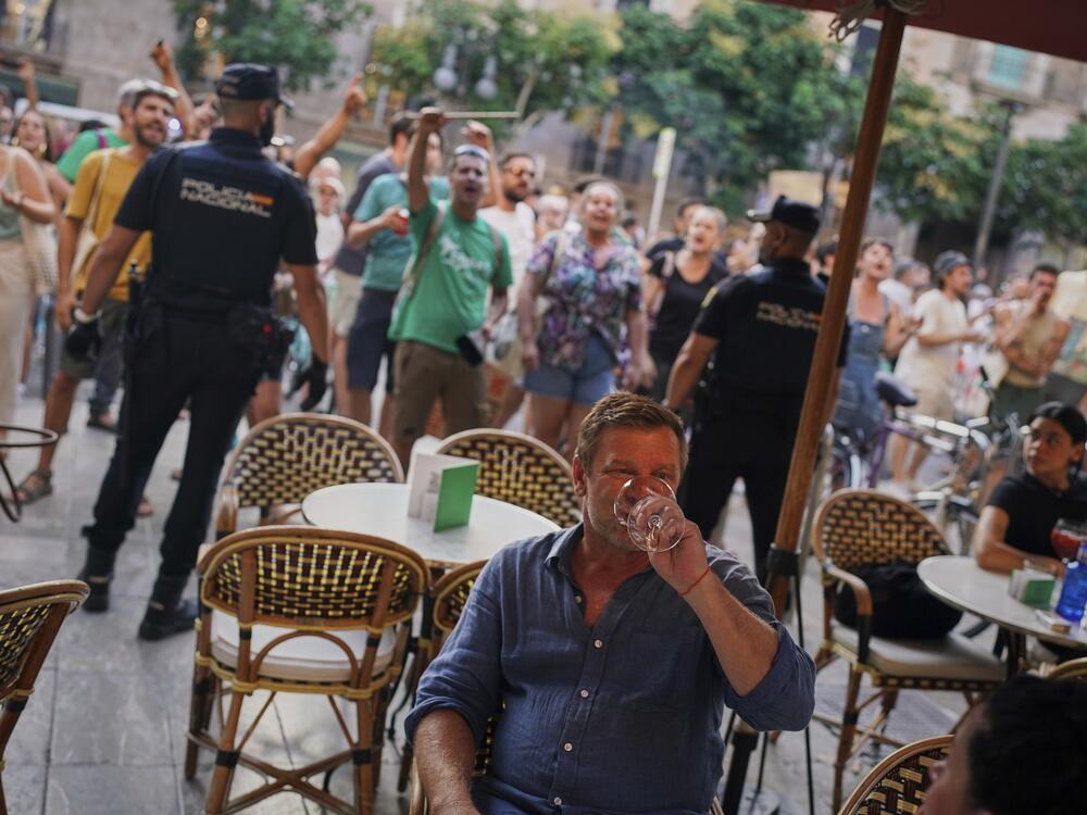 Tourists sit in a restaurant as people protest against overtourism in the Balearic island of Mallorca, Spain on Sunday.