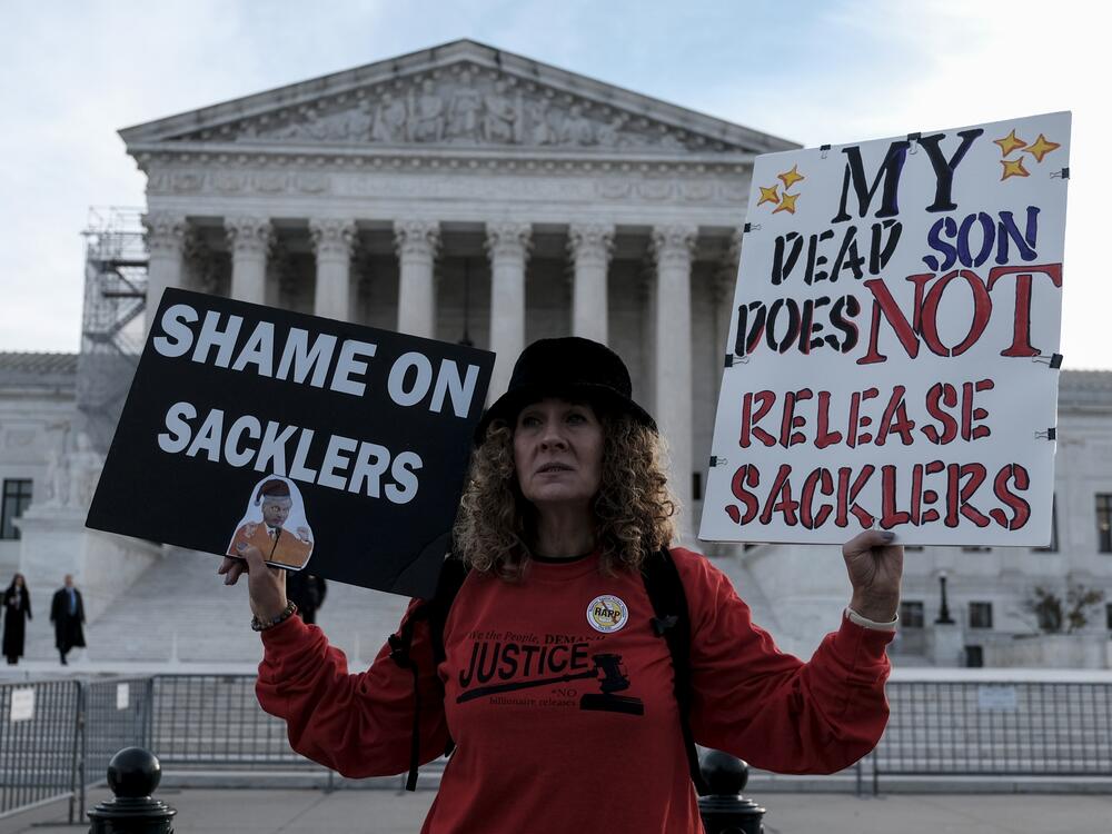 Grace Bisch hold a picture of stepson Eddie Bisch who died as a result of an overdose on outside of the U.S. Supreme Court on December 4, 2023  in Washington, D.C. The Supreme Court overturned a previous version of the Purdue Pharma-Sackler bankruptcy plan, leading to a new deal now under review.