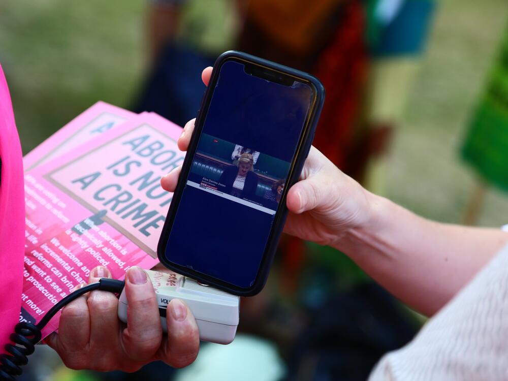 Protesters from 'Abortion Rights' watch Alex Davies-Jones, Parliamentary under-secretary of state at the Ministry of Justice, talk in the House of Commons as they gather near Parliament, where MPs are voting on the decriminalization of abortion on June 17 in London.