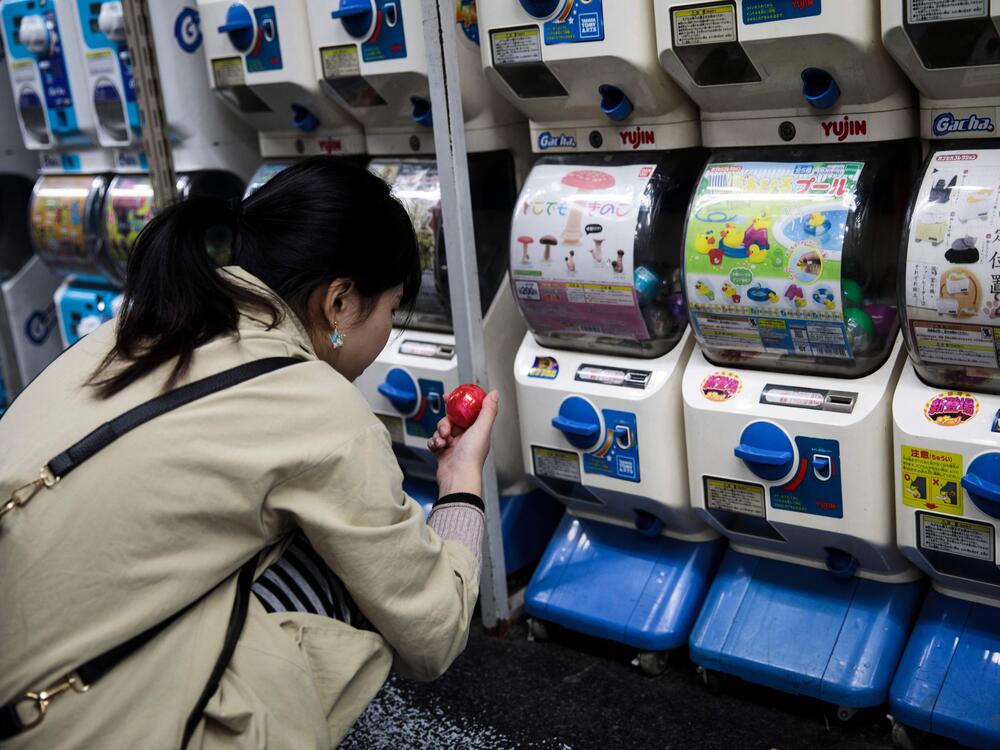 In this picture taken on Nov. 14, 2017, a woman looks at her newly-dispensed item in her hunt for capsule toys at a store in Tokyo's Akihabara district.
