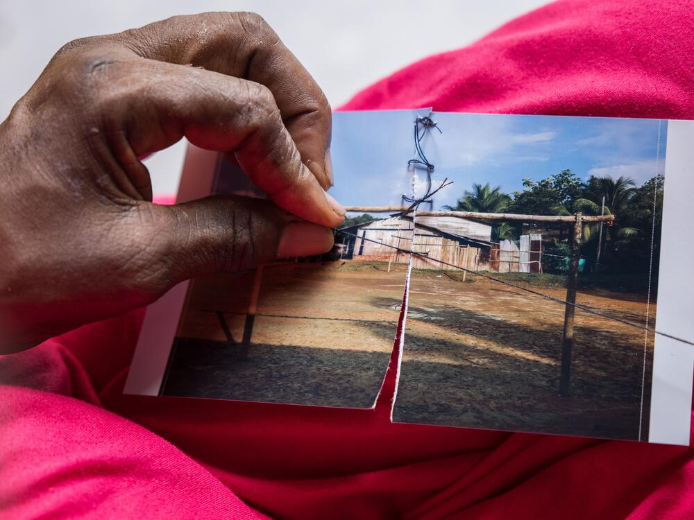 Carmen Fidela Mena, a healer and midwife, sews up a photo as a symbolic way of healing the community's suffering.