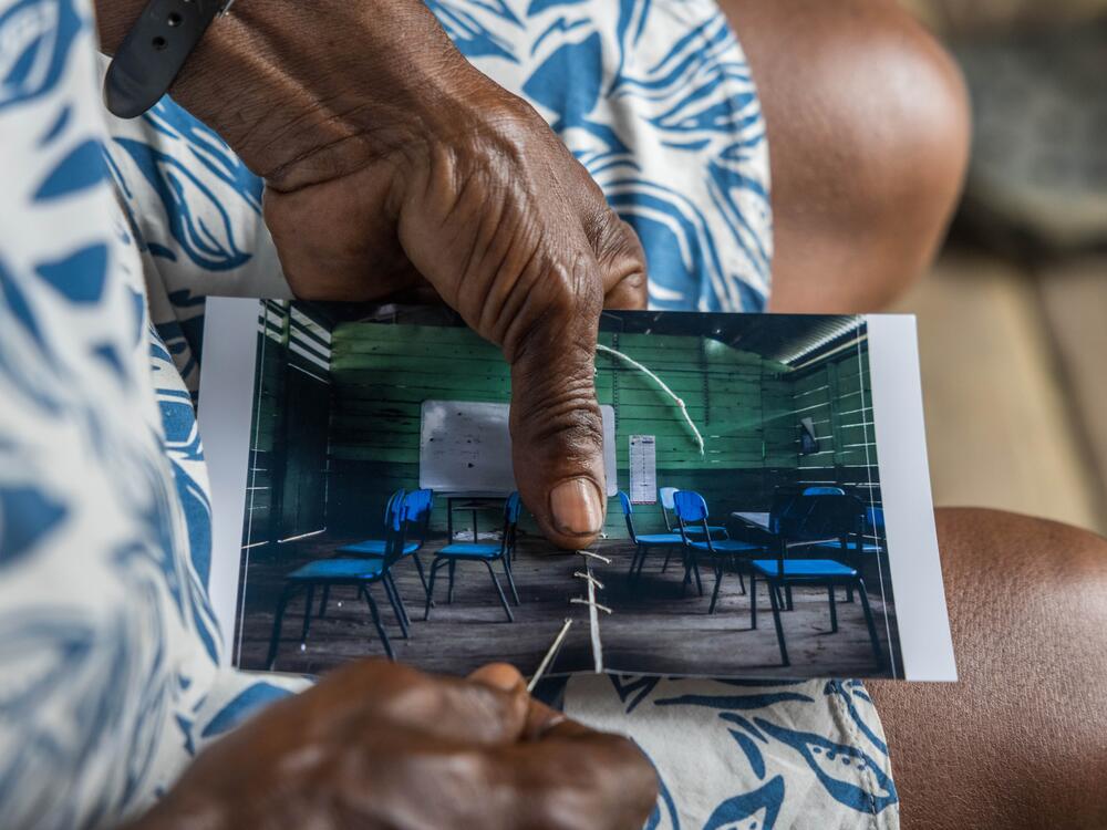Margarita Rojas Mena, in Mojaudó, stitched up the photograph of the community school, wounded by bullets from an armed confrontation.