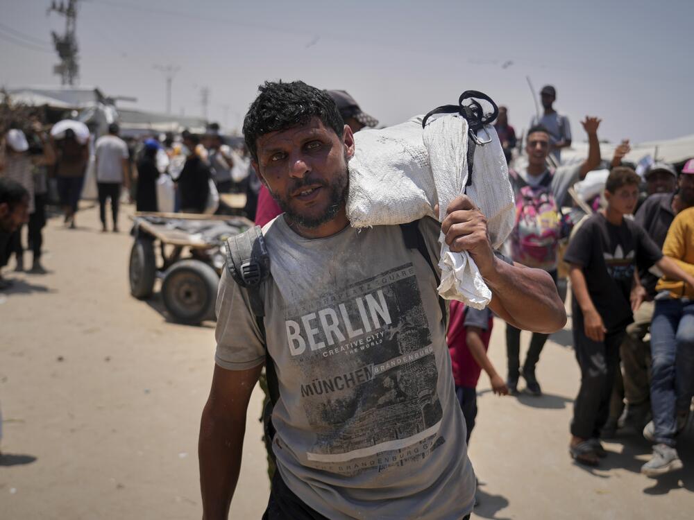 Omar al-Hobi, 43, from Rafah, carries a bag of food he collected at a distribution center run by private contractor the Gaza Humanitarian Foundation in the southern Gaza Strip, as he arrives at his tent in Khan Younis, on June 10.