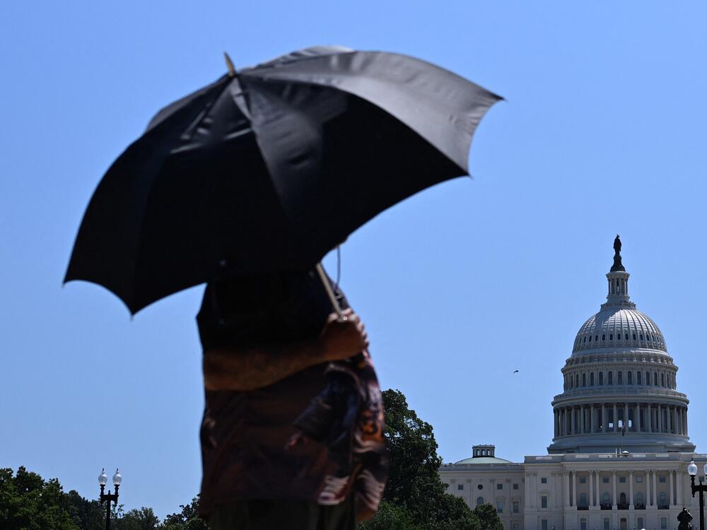 A person uses an umbrella as they walk near Capitol Hill in Washington, D.C., on Friday. The United States is experiencing its first significant heat wave of the year, across the Great Plains and expanding into parts of the Midwest and Great Lakes over the weekend, according to the National Weather Service.