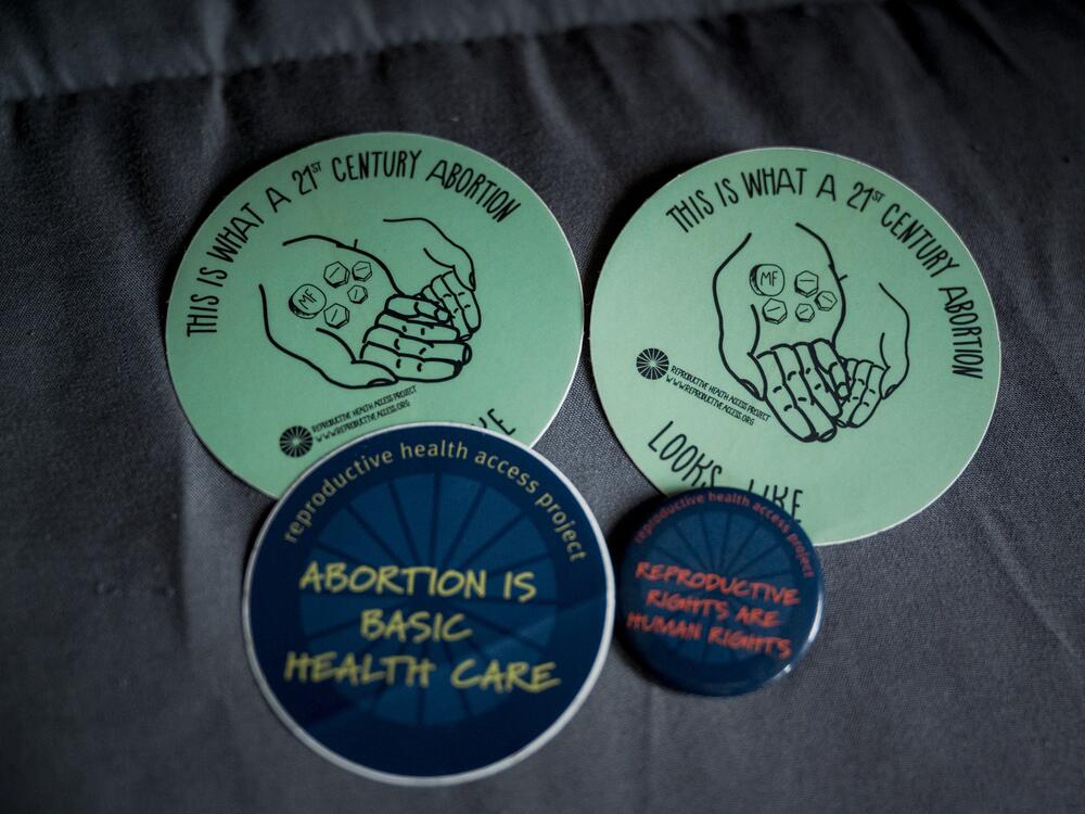 Abortion care stickers and a reproductive rights pin from Dr. Maya Bass.