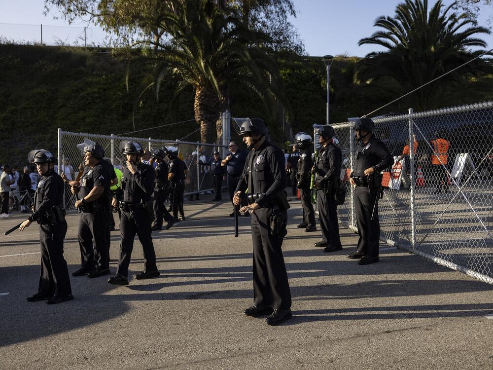 Police officers stand guard as they close the gate of the main entrance of Dodger Stadium faced with protesters on Thursday.